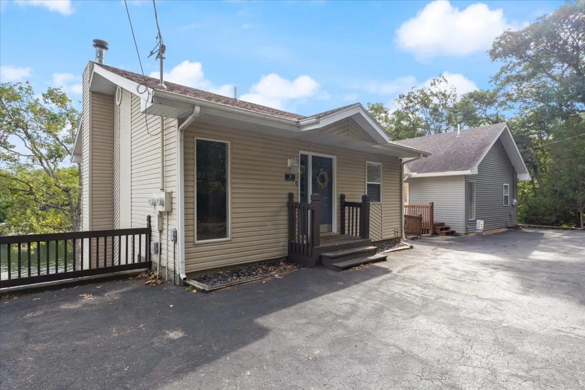 A welcoming view of the home's front porch, featuring large windows and a spacious driveway, suggesting easy arrival and comfortable outdoor relaxation. The inviting setup hints at shared gatherings and the start of a memorable stay.