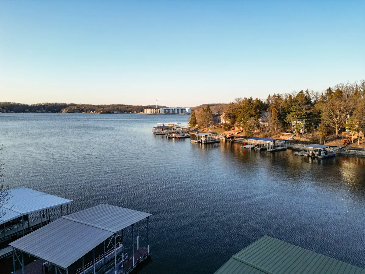 A scenic lake view framed by docks and surrounding trees, evoking a peaceful and inviting setting. The image highlights the natural beauty of the lake, suggesting both quiet mornings and lively afternoons spent outdoors.