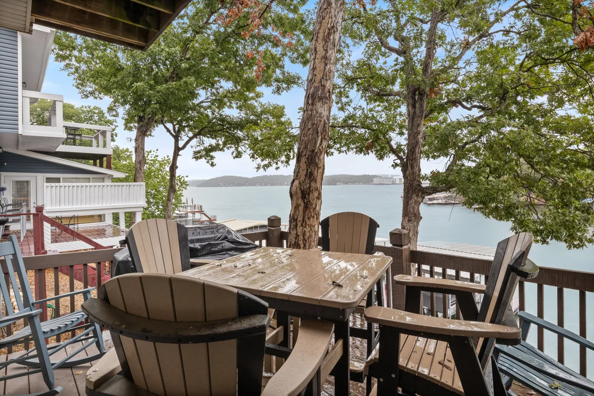 An outdoor seating area overlooking the lake, surrounded by trees, with tranquil water views. The setting is perfect for relaxation, socializing, and enjoying nature, with evening sky and stargazing potential.