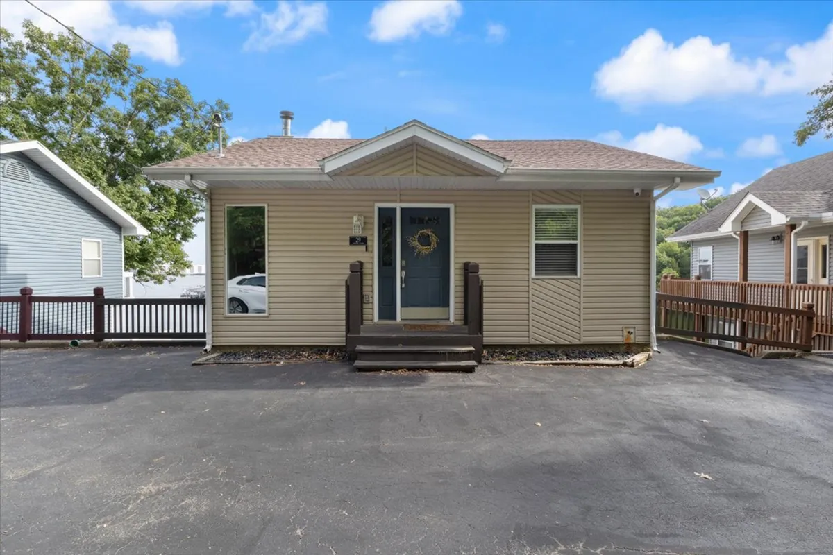 This image features the home's front porch with a welcoming blue door adorned by a wreath, set against a backdrop of lush greenery. The inviting entryway hints at both approachability and secure access.