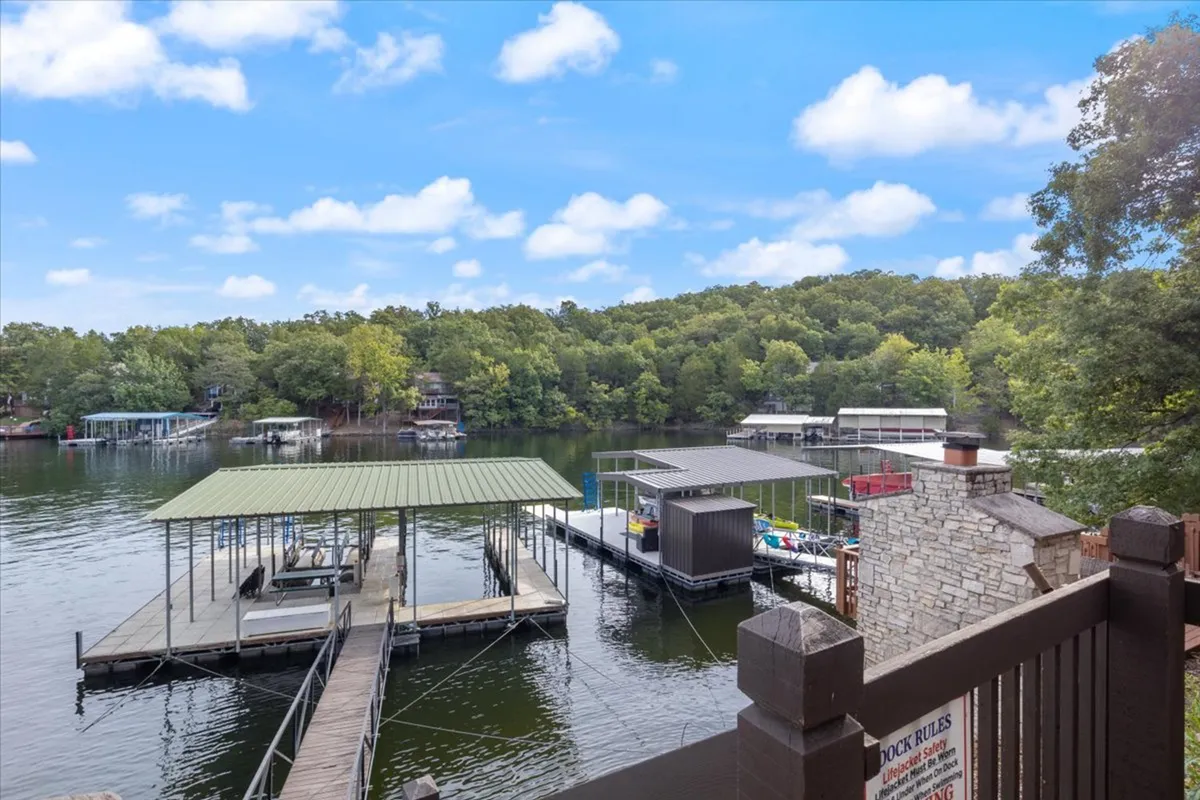 A dock extends out onto serene water, ringed by lush trees and an open sky, suggesting opportunities for fishing, boating, and waterfront fun. The mood is peaceful and restorative.